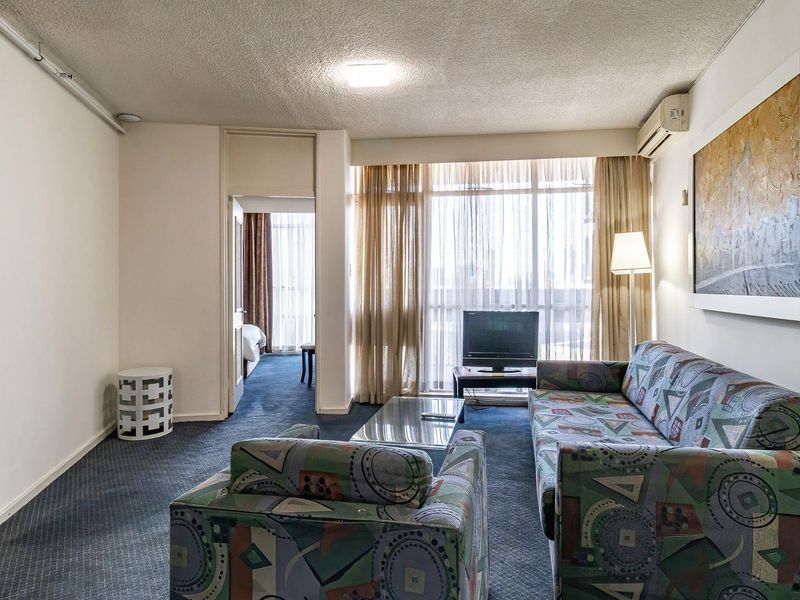 A living room featuring carpet flooring, a textured ceiling, and a sliding glass door leading to a balcony, with an integrated air conditioning unit.