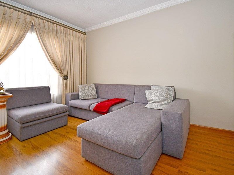 A living room featuring laminate flooring and crown molding, providing a neutral base for interior design updates.