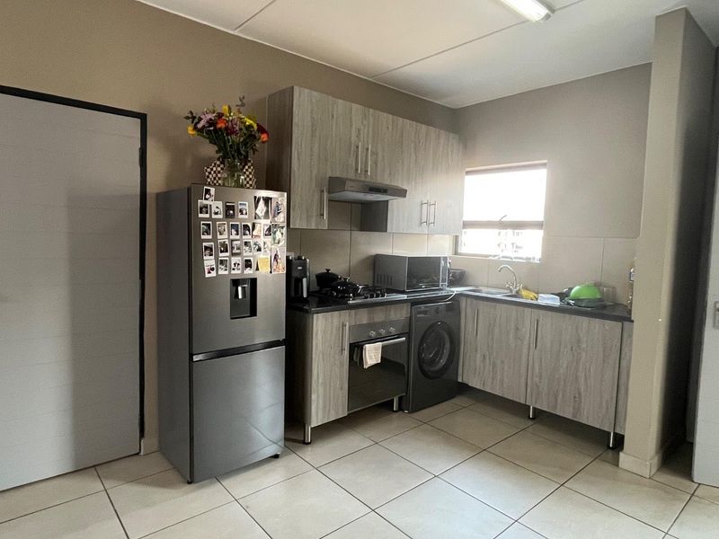 A functional kitchen featuring wood-look cabinetry, dark countertops, built-in oven and hob, and tiled flooring, providing a practical workspace for daily cooking.