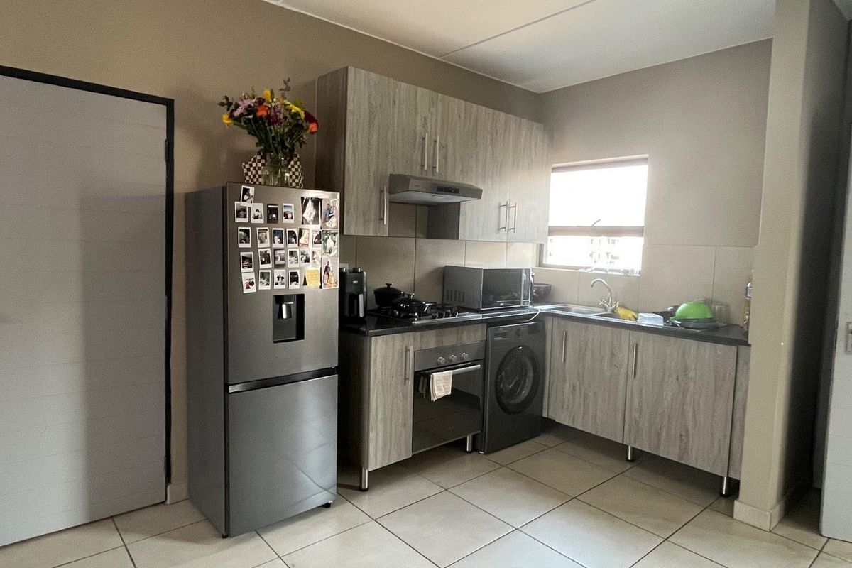 A functional kitchen featuring wood-look cabinetry, dark countertops, built-in oven and hob, and tiled flooring, providing a practical workspace for daily cooking.
