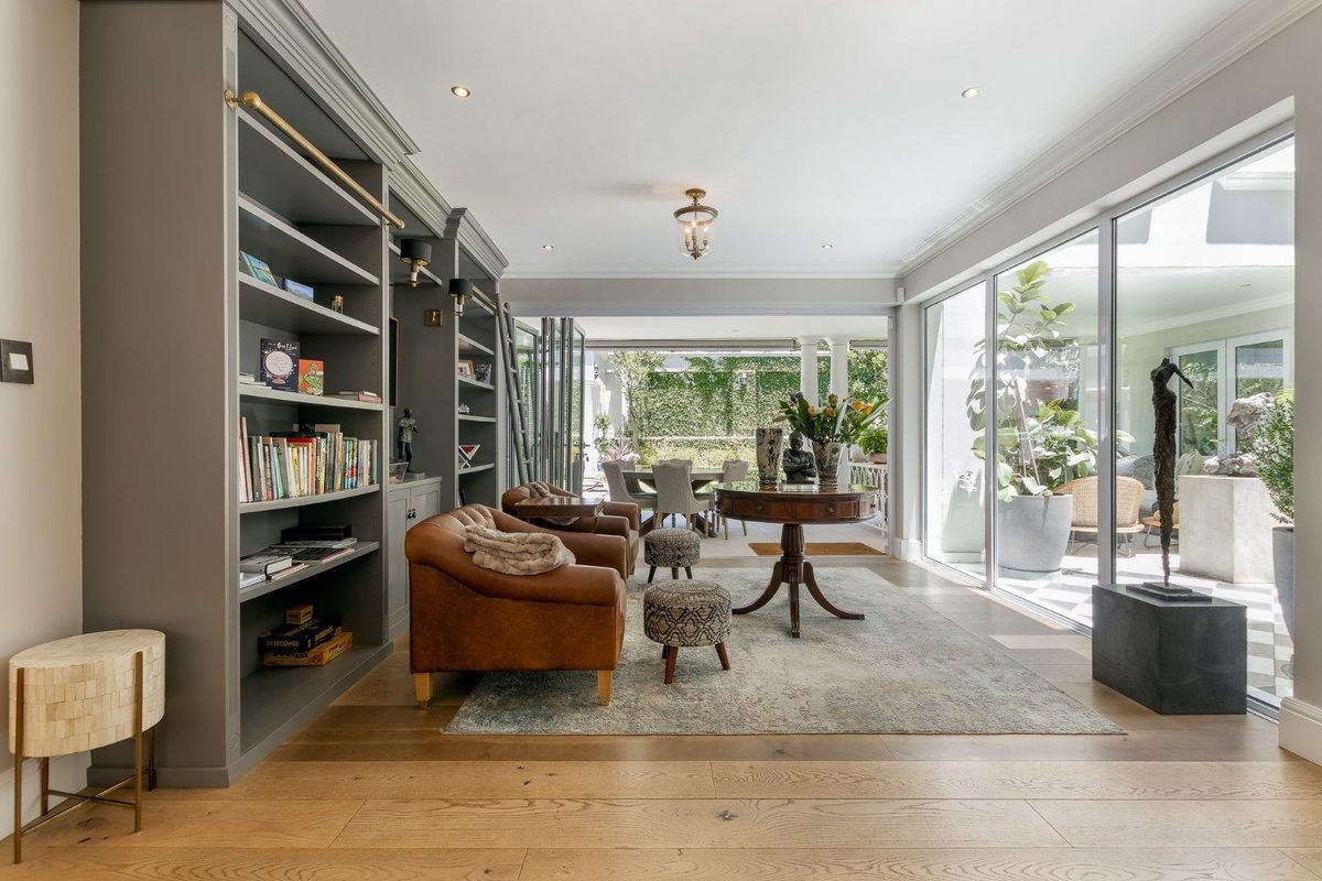 Elegant living room featuring custom built-in floor-to-ceiling shelving, hardwood flooring, and large sliding glass doors opening to a covered patio area.