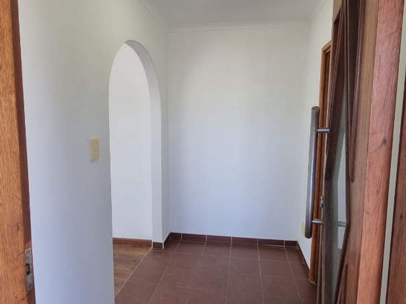A clean and simple entrance hall featuring tiled flooring and a classic archway leading into the home.
