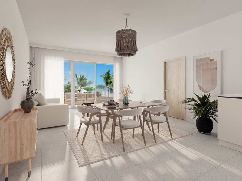 Bright open-plan living and dining area featuring large sliding glass doors that open to a private balcony with tropical views.