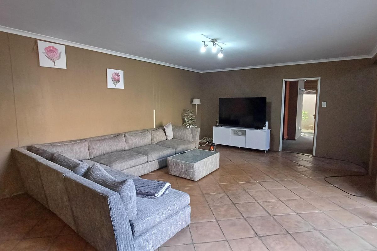 Spacious living room featuring neutral wall tones, tiled flooring, and direct access to outdoor areas through a sliding glass door.