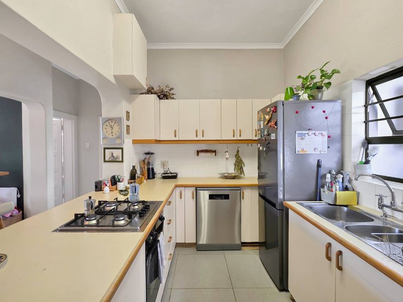 Functional kitchen featuring built-in cabinetry, gas hob, integrated dishwasher, and double bowl sink with tiled backsplash and flooring.