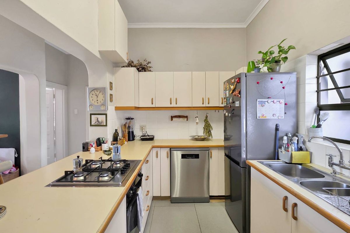 Functional kitchen featuring built-in cabinetry, gas hob, integrated dishwasher, and double bowl sink with tiled backsplash and flooring.