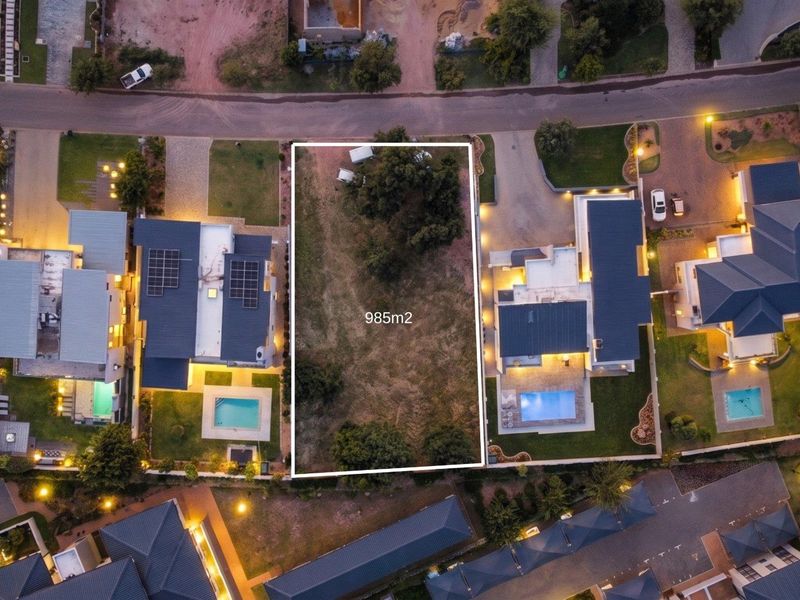 An aerial view of a 985m2 vacant residential plot situated between two developed properties in a residential estate.