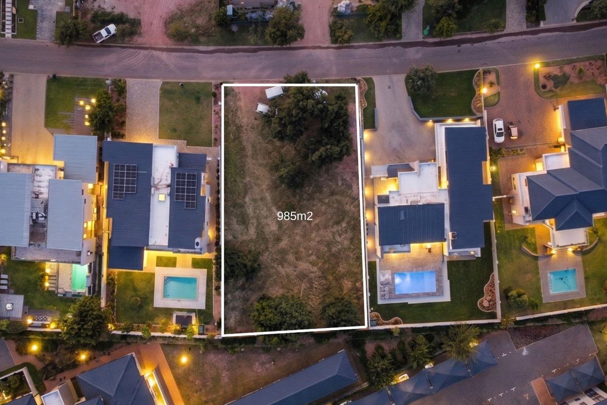 An aerial view of a 985m2 vacant residential plot situated between two developed properties in a residential estate.