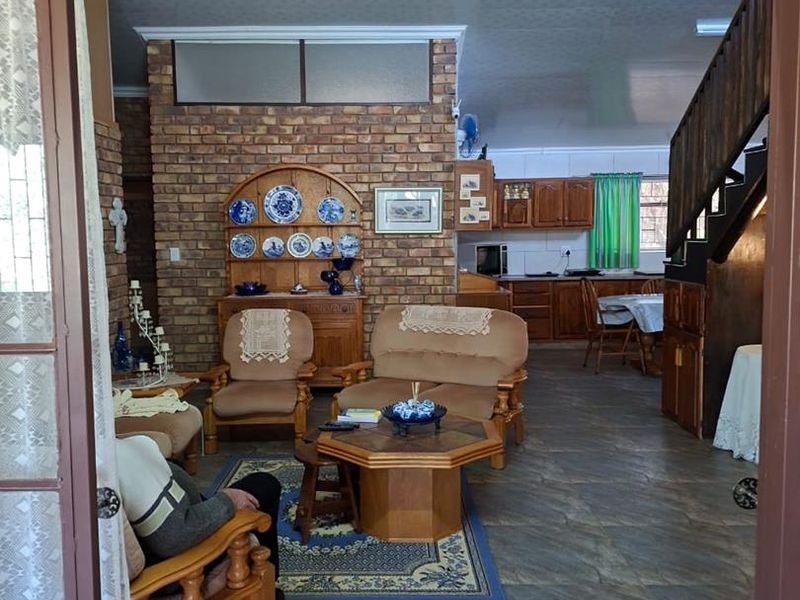 Open plan living and kitchen area featuring exposed brick walls, tiled flooring, and a timber staircase leading to the upper level.