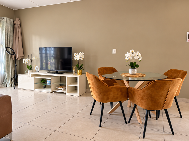 A bright and well-maintained living area featuring neutral tiled flooring, large sliding glass doors with security gates, and ample natural light.