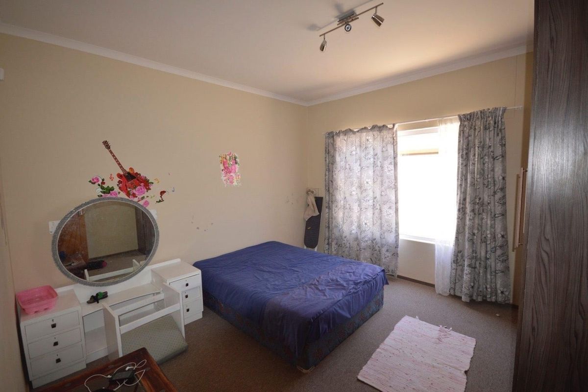 A standard bedroom featuring carpeted flooring, a window with curtains, and built-in cabinetry.