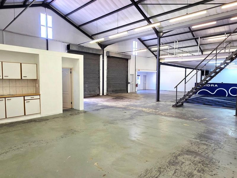 Spacious industrial warehouse unit featuring a mezzanine level, roller shutter doors, kitchenette area, and private restroom facilities.