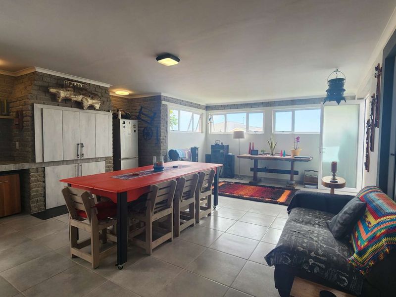 Spacious open-plan living and dining area featuring exposed brick walls, tiled flooring, and large sliding glass doors providing ample natural light.