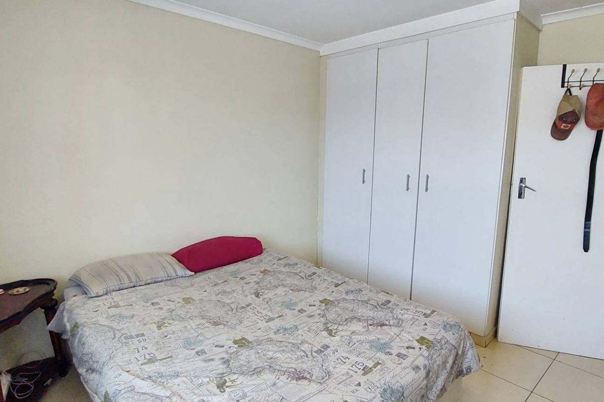 A functional bedroom featuring built-in cupboards, tiled flooring, and direct access to an adjoining bathroom.