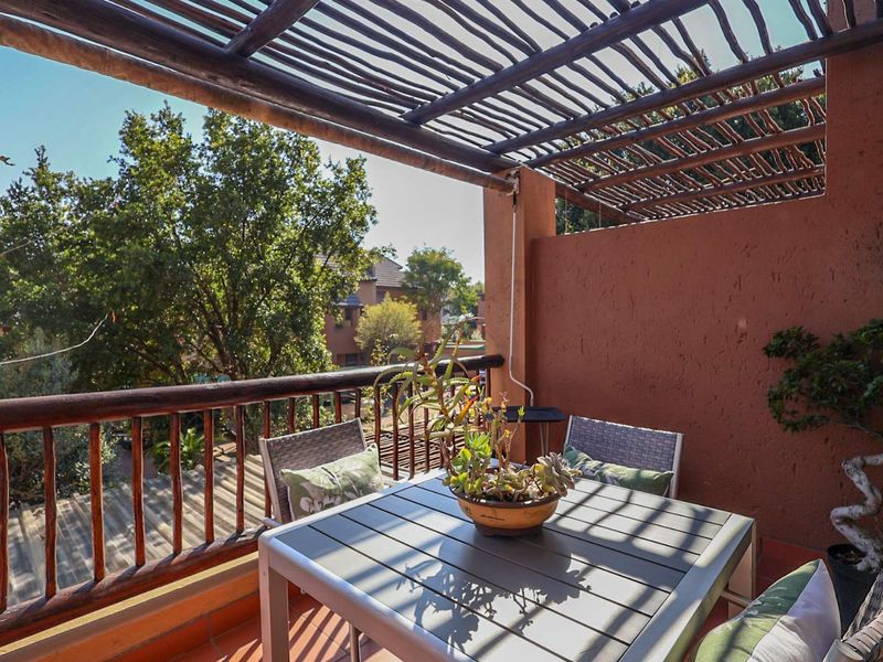 A covered balcony featuring a rustic wooden pergola, wooden balustrade, and tiled flooring, offering an outdoor space for relaxation.