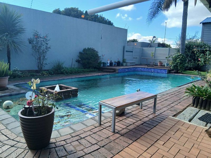 Outdoor pool area featuring a built-in water feature, brick paved surround, and perimeter boundary walling.
