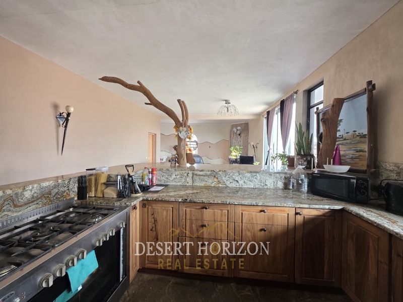Open plan kitchen featuring granite countertops, wooden cabinetry, and a built-in gas stove, seamlessly flowing into the adjacent living area.