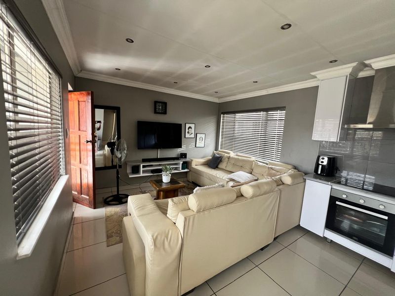 Open-plan living area featuring tiled floors, recessed lighting, and a compact kitchen with built-in oven and extractor fan.