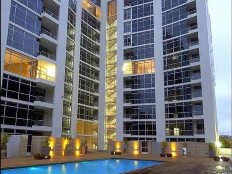 Modern apartment complex featuring a swimming pool and timber deck area with integrated lighting and extensive glass facade architecture.