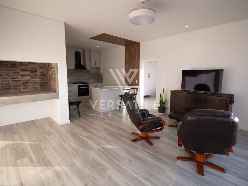 Spacious open-plan living area featuring a built-in fireplace, modern kitchen with island, and light wood-look tile flooring throughout.