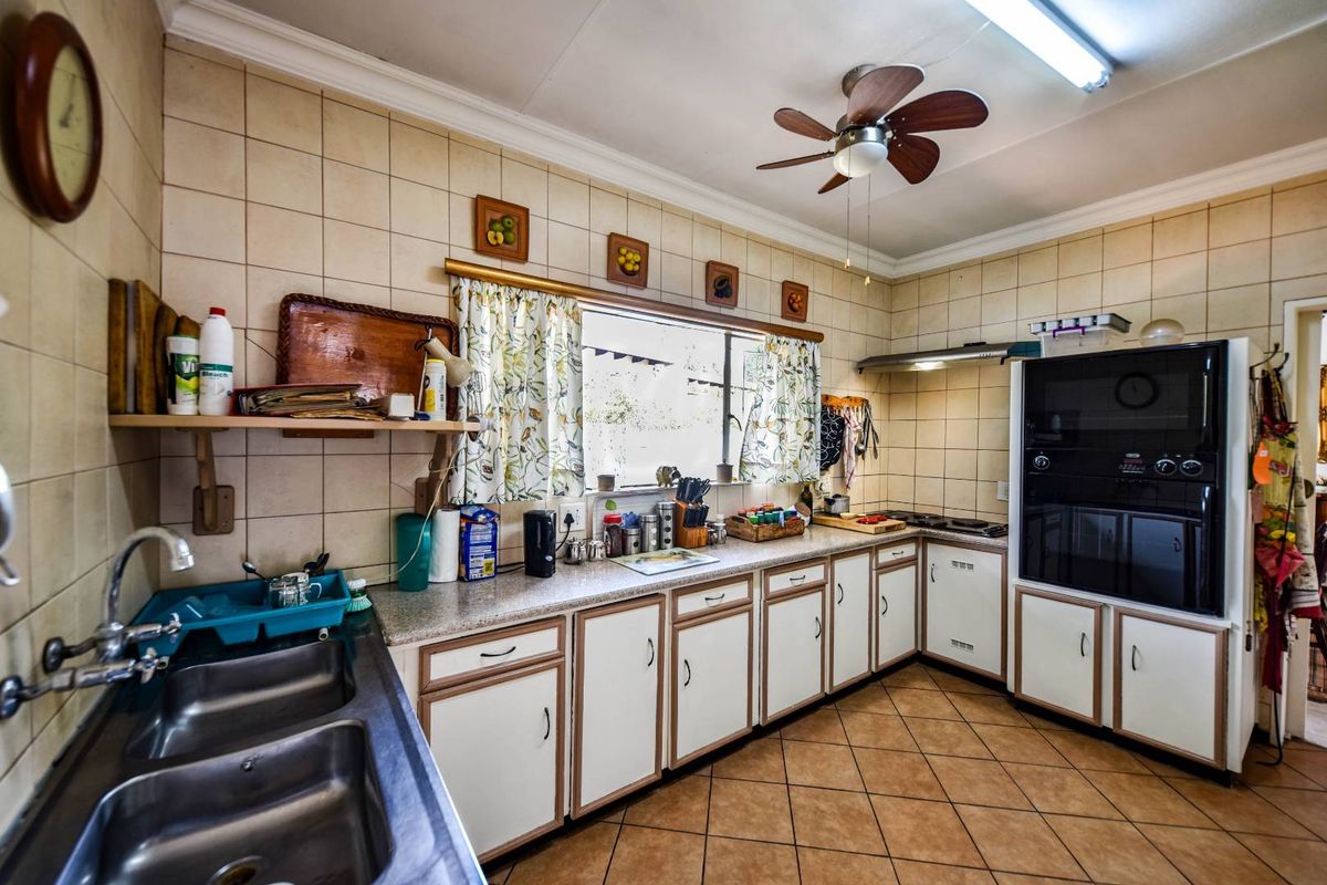 A functional kitchen featuring built-in cabinetry, a double sink, integrated oven, and hob, with tiled splashbacks and flooring throughout.