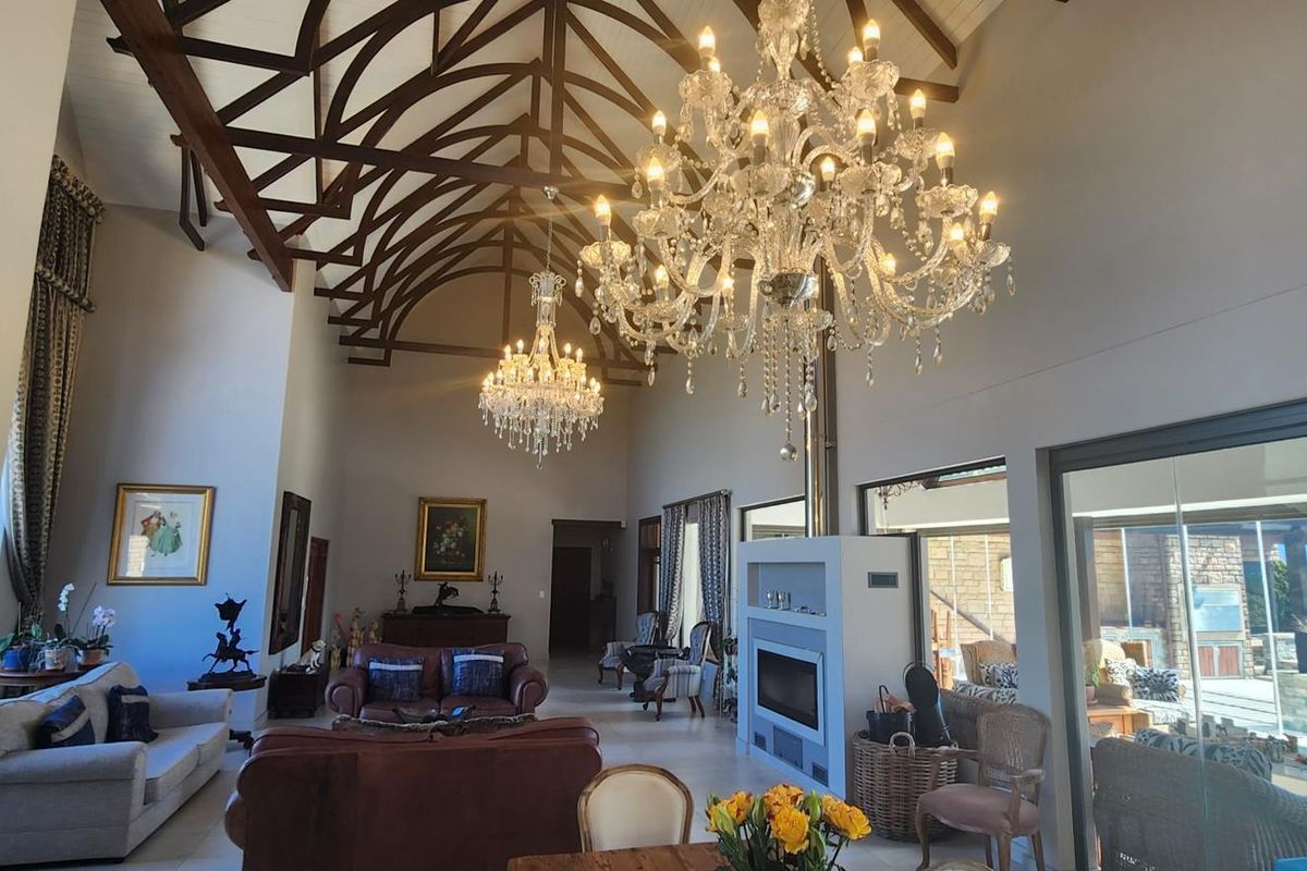 Spacious living area featuring high vaulted timber-truss ceilings, a modern built-in fireplace, and large glass sliding doors opening to an outdoor patio.