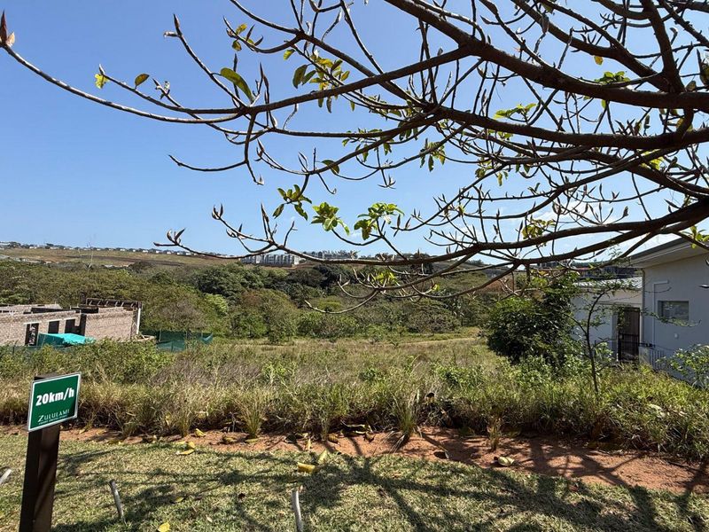 A view of a vacant residential plot featuring natural vegetation and surrounding estate landscape.