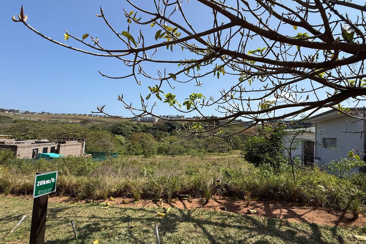 A view of a vacant residential plot featuring natural vegetation and surrounding estate landscape.
