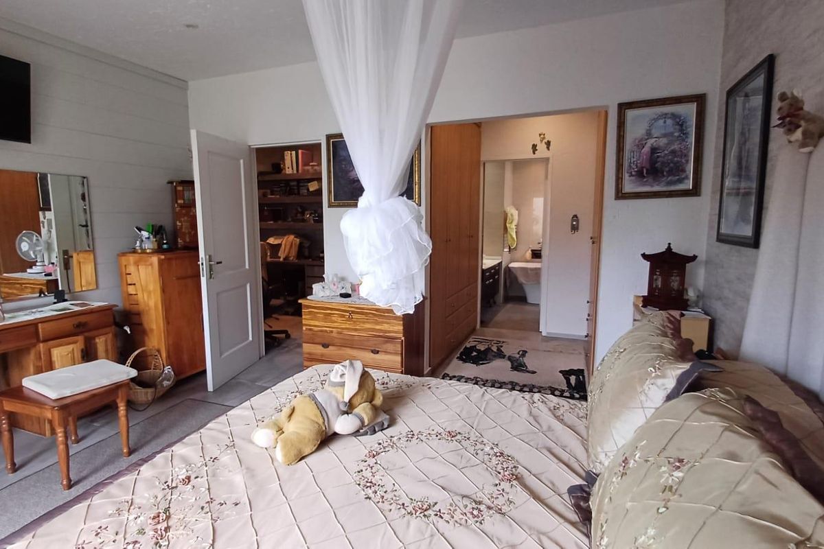 Spacious bedroom featuring built-in cupboards and direct access to an en-suite bathroom, offering a functional layout with neutral finishes.