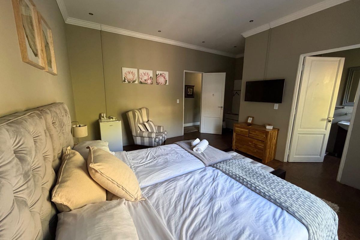 A well-maintained guest bedroom featuring neutral wall tones, crown molding, recessed lighting, and direct access to an en-suite bathroom.