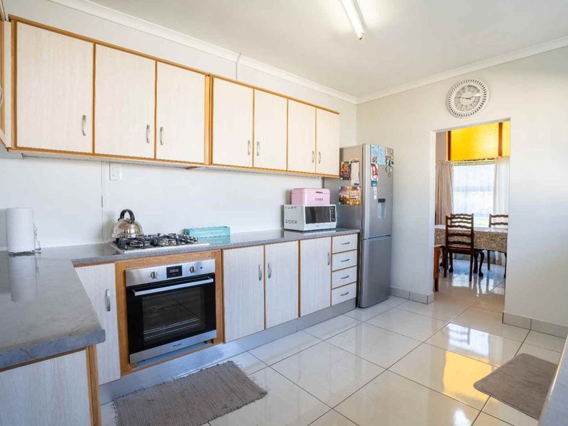 A functional kitchen featuring light-toned cabinetry, laminate countertops, a built-in oven, gas cooktop, and tiled flooring, with an open transition to the dining area.