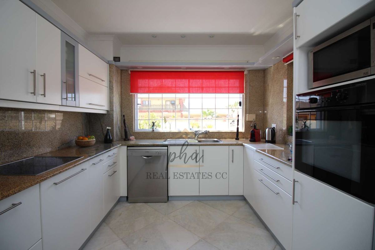 A well-appointed kitchen featuring granite countertops, white cabinetry, integrated oven, built-in microwave, and a stainless steel dishwasher.