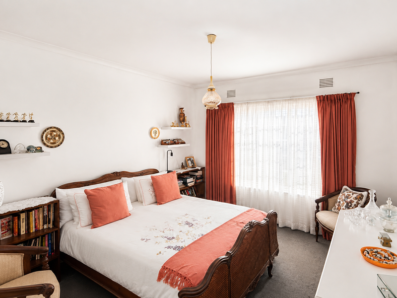 A well-maintained bedroom featuring carpeted flooring, cove cornicing, and built-in shelving, offering a comfortable and functional living space.