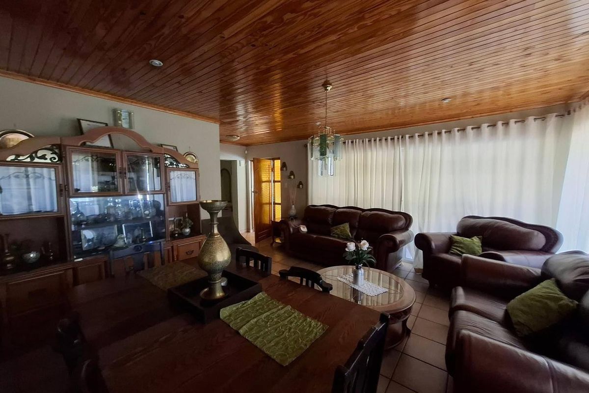 Spacious living area featuring a warm timber-clad ceiling, tiled flooring, and large glass sliding doors that provide ample natural light.