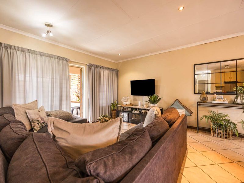 A comfortable living room featuring tiled flooring, recessed lighting, and a sliding glass door providing access to the outdoor patio area.