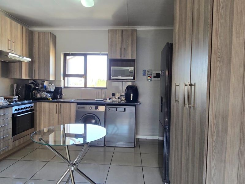 Modern kitchen featuring wood-grain cabinetry, integrated appliances, tiled flooring, and ample storage space, creating a functional and contemporary culinary environment.