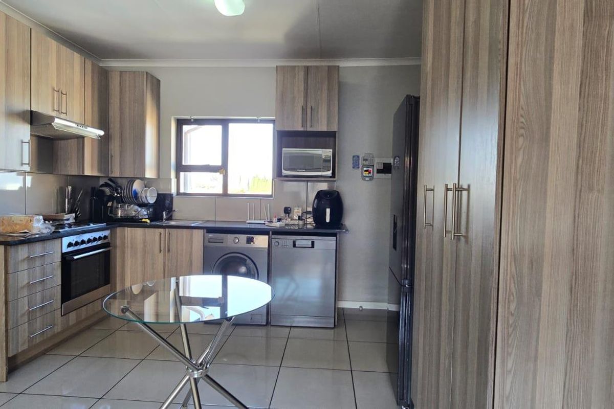 Modern kitchen featuring wood-grain cabinetry, integrated appliances, tiled flooring, and ample storage space, creating a functional and contemporary culinary environment.