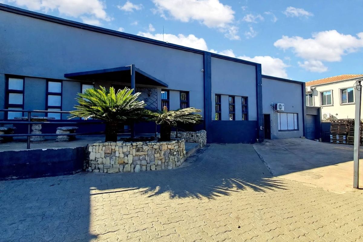 Front exterior view of a commercial building featuring a paved driveway, stone-clad planters, and a covered entrance area.