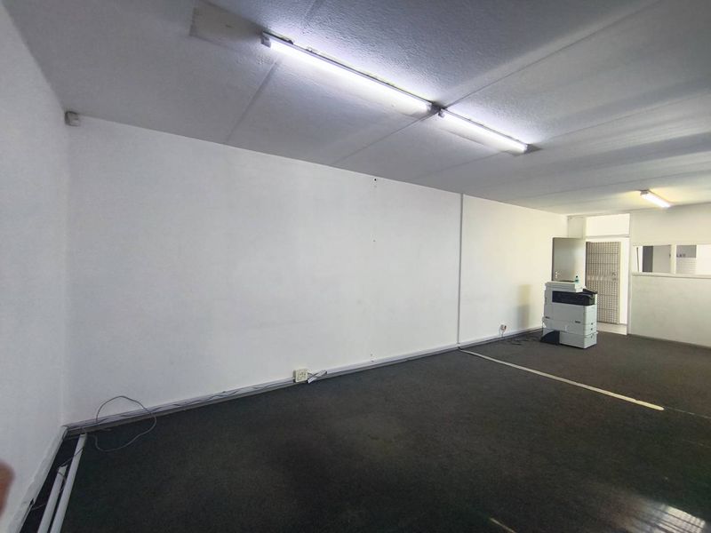 A vacant industrial office space featuring fluorescent lighting and carpeted flooring, suitable for a variety of commercial or administrative uses.