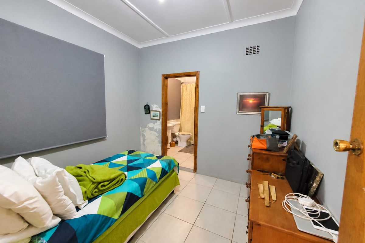 Bedroom featuring tiled flooring and direct access to an en-suite bathroom, showing visible wall surface damage requiring repair.