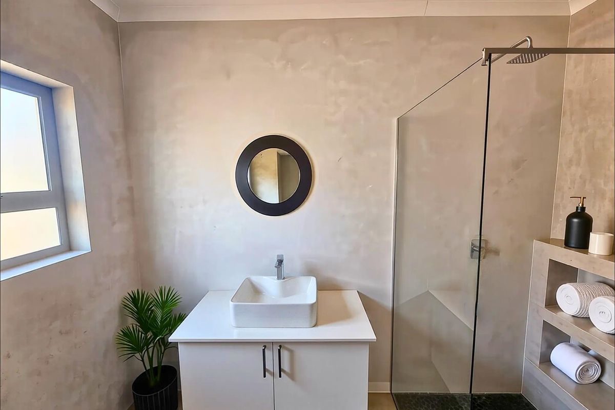 Modern bathroom featuring a floating vanity with a square vessel sink, a frameless glass shower enclosure with a rainfall showerhead, and textured wall finishes.