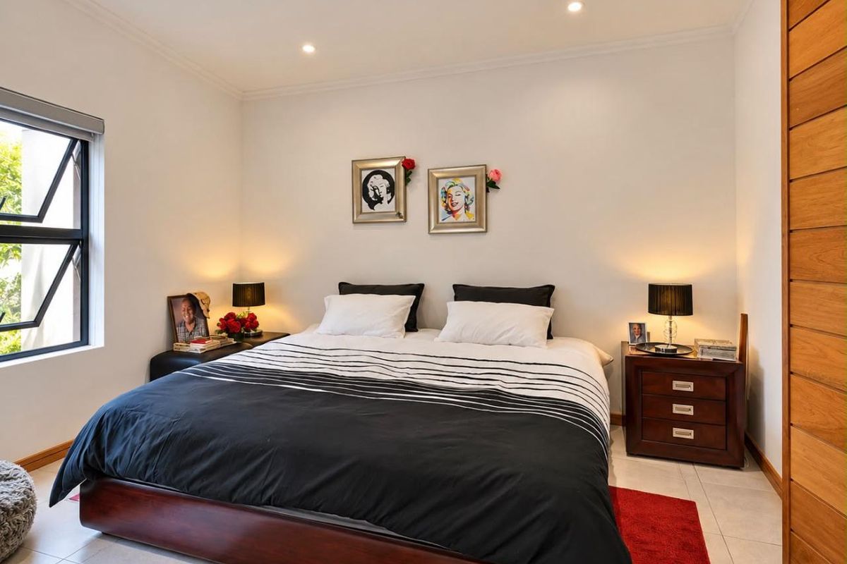 A well-maintained bedroom featuring tiled flooring, recessed downlighting, and a large built-in wooden wardrobe.