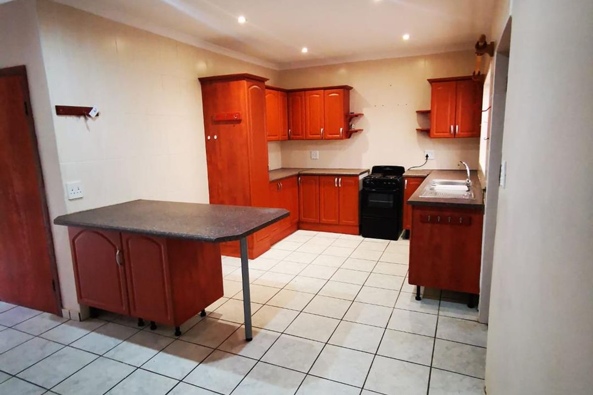 A functional kitchen featuring wooden cabinetry, a built-in stove, a breakfast nook island, and tiled flooring throughout.