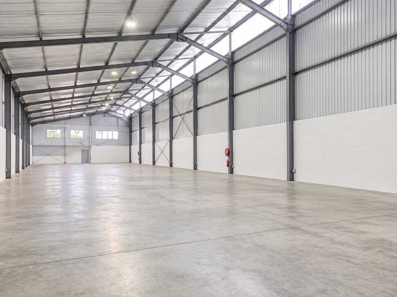 Spacious industrial warehouse unit featuring a high-clearance steel portal frame, concrete flooring, and ample natural light through integrated skylights.