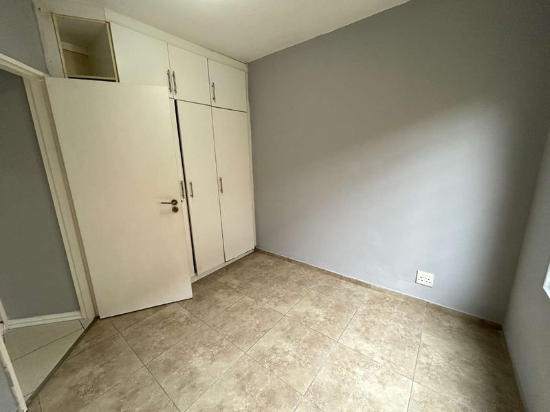 A vacant bedroom featuring tiled flooring and built-in cupboards, offering a neutral canvas ready for personalization.