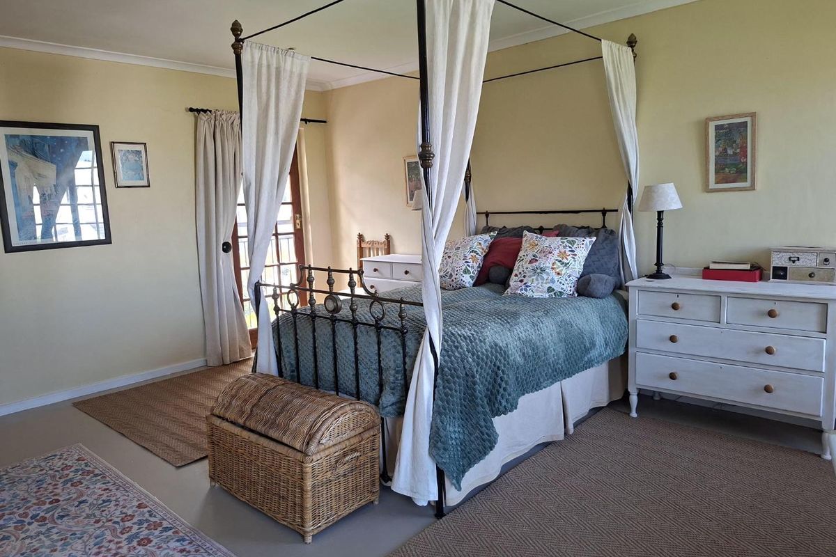 Spacious bedroom featuring neutral wall tones, coved ceiling cornicing, and direct access to an outdoor area through a timber-framed glass door.