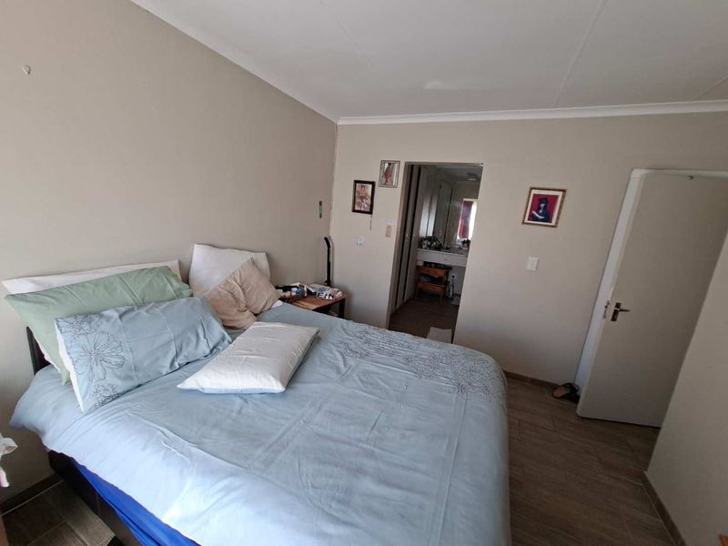 A functional bedroom featuring tiled flooring and neutral wall tones, with direct access to an adjoining bathroom area.