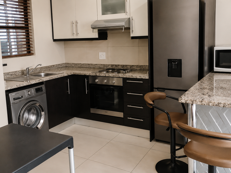 Modern kitchen featuring granite countertops, built-in oven and hob, extractor fan, and integrated cabinetry with a convenient breakfast bar area.