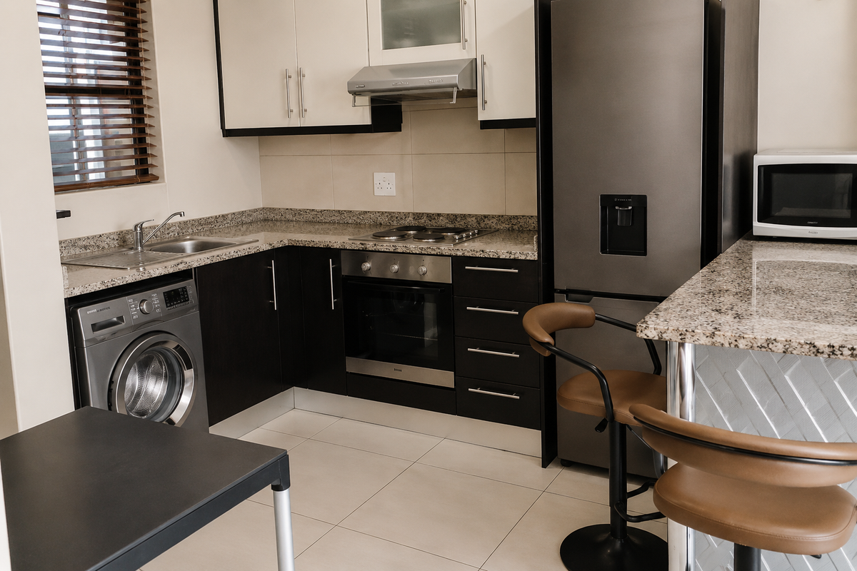 Modern kitchen featuring granite countertops, built-in oven and hob, extractor fan, and integrated cabinetry with a convenient breakfast bar area.