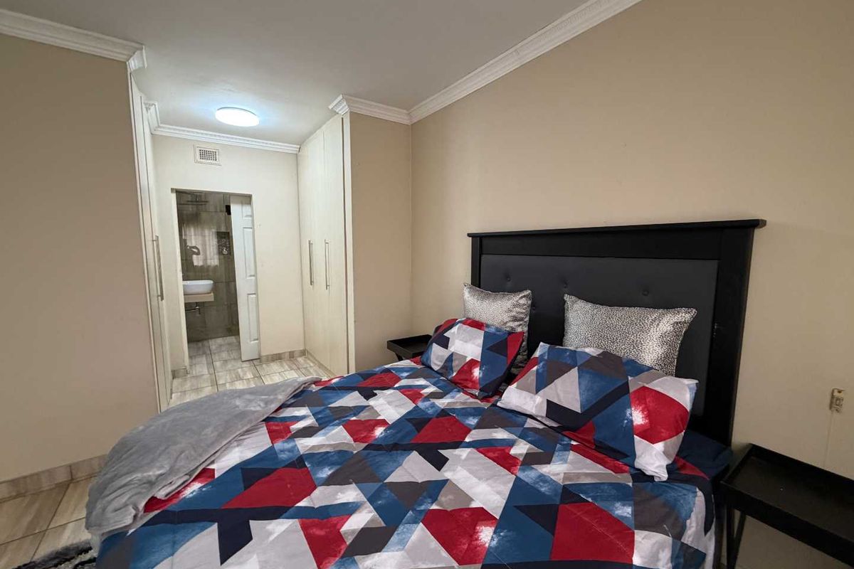 A bedroom featuring built-in cupboards, crown molding, and an en-suite bathroom with tiled flooring.
